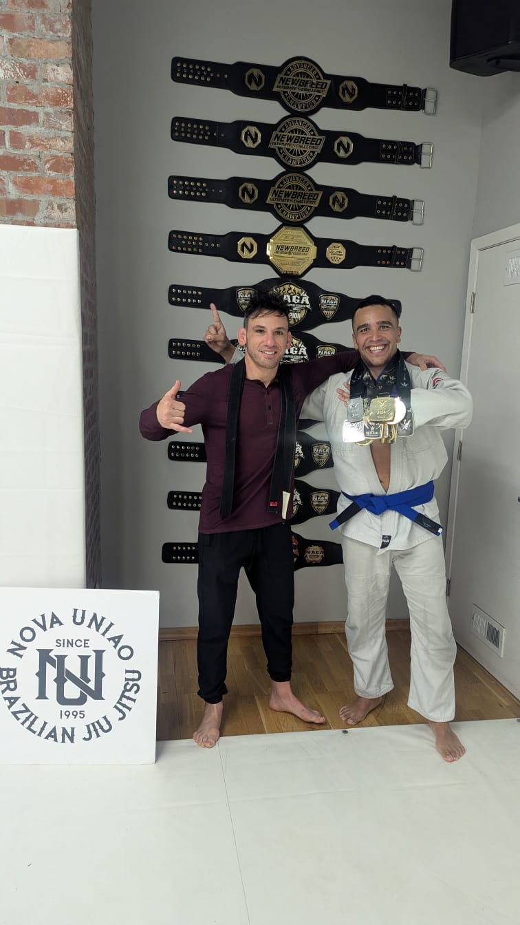 Brian Patnode with his coach in front of a wall of championship belts at Nova Uniao